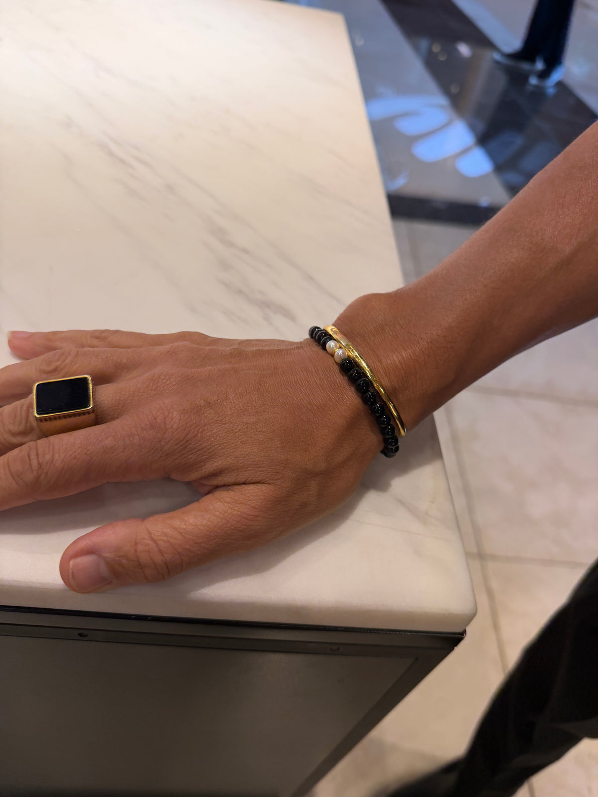 Black beaded pearl bracelet worn at a counter