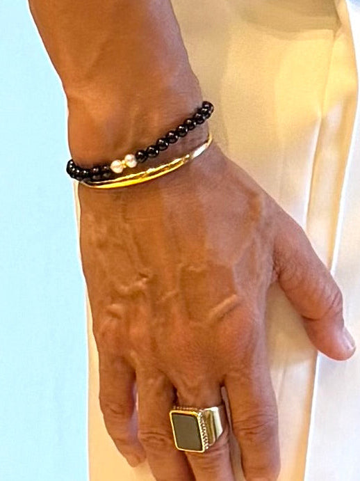 Black pearl bracelet worn with a gold bangle